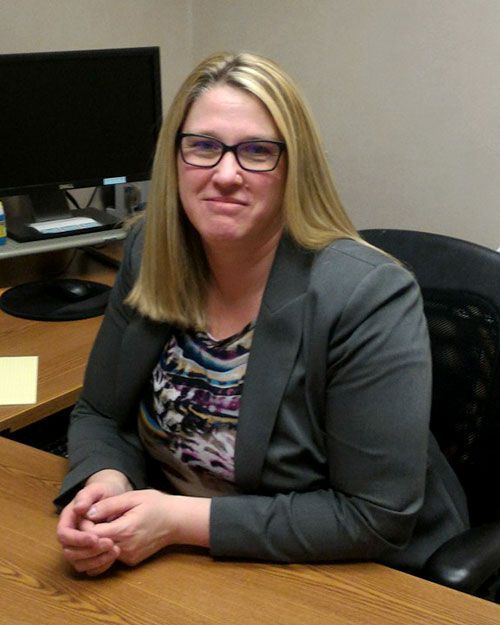 A woman wearing glasses is sitting at a desk in front of a computer