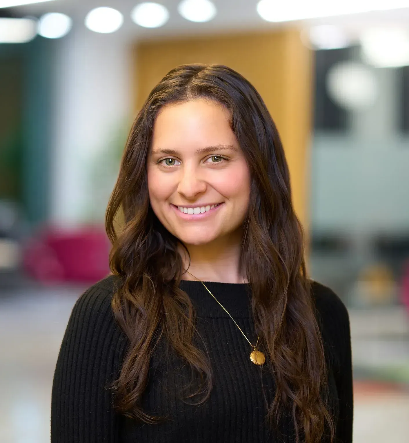 A woman with brown hair and a gold necklace is smiling for the camera.
