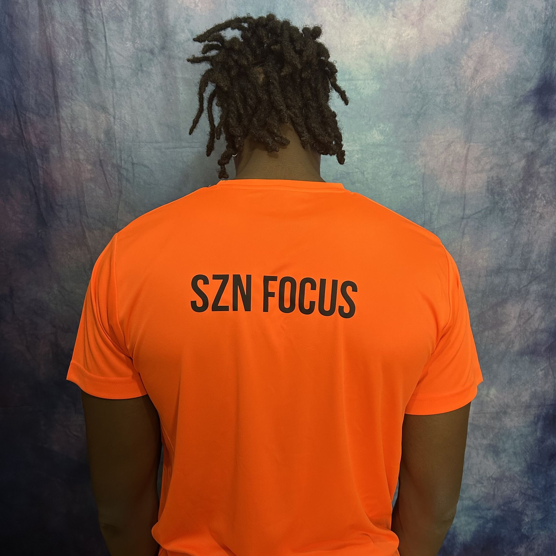 Orange t-shirt with a black graphic of a lightbulb with a target in the center.