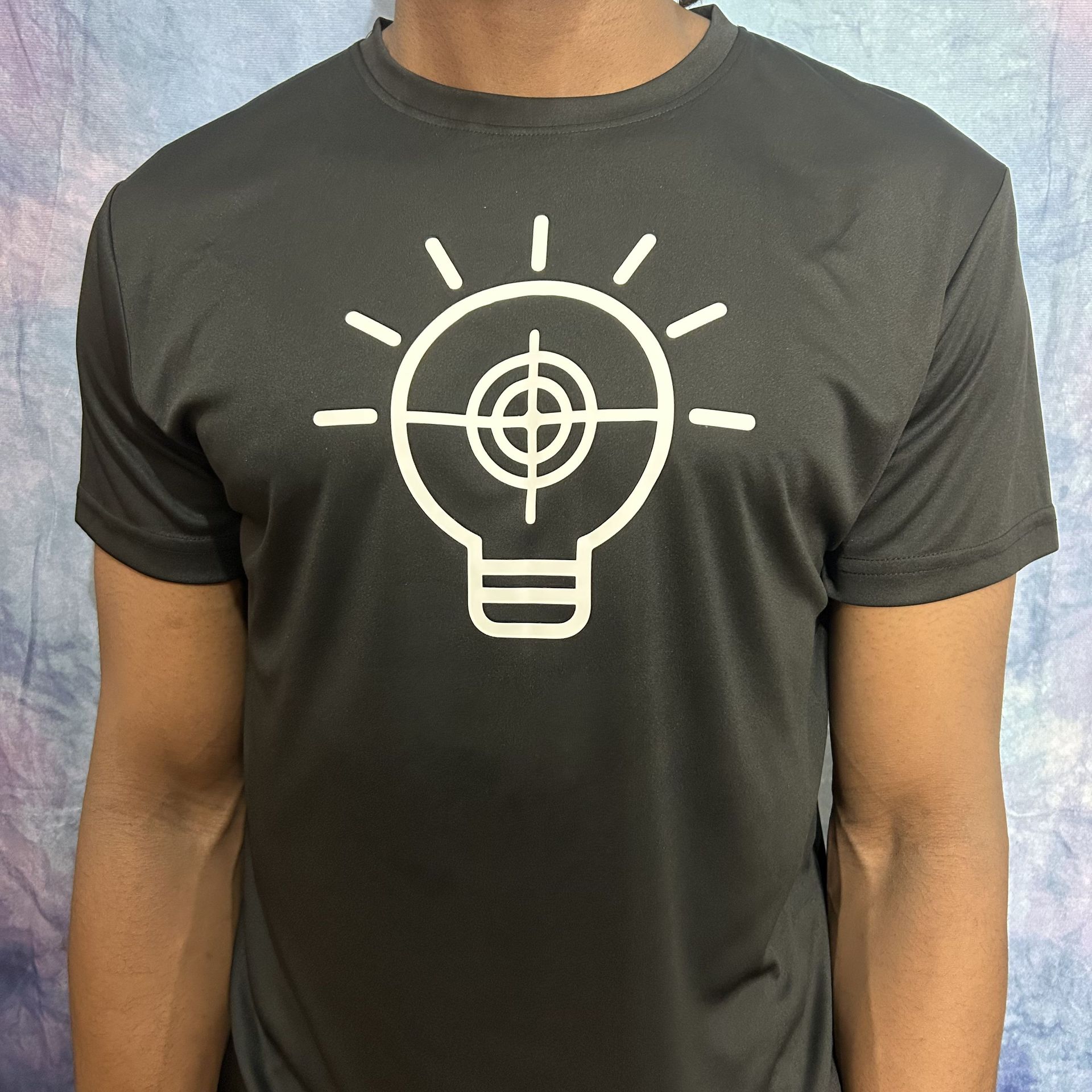 Black t-shirt with a white graphic of a lightbulb containing a target.