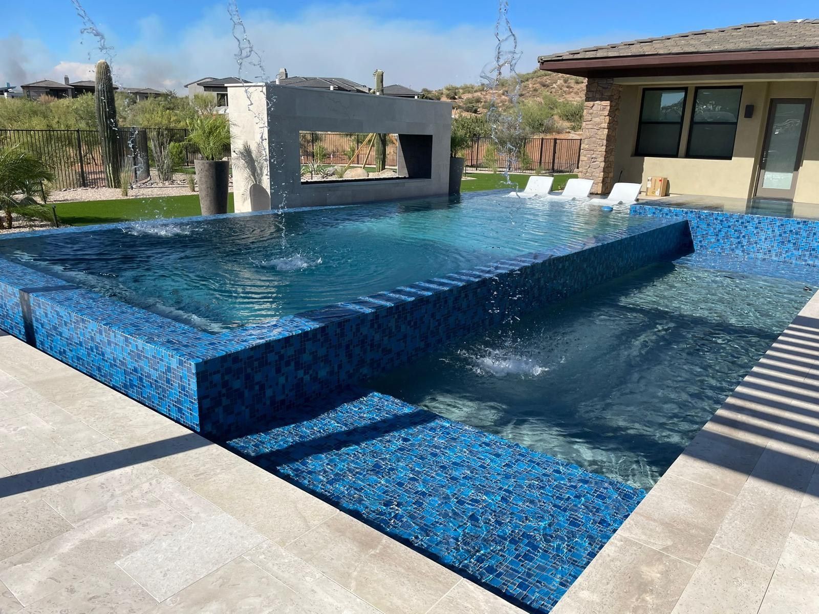 A large swimming pool with blue tiles in front of a house.