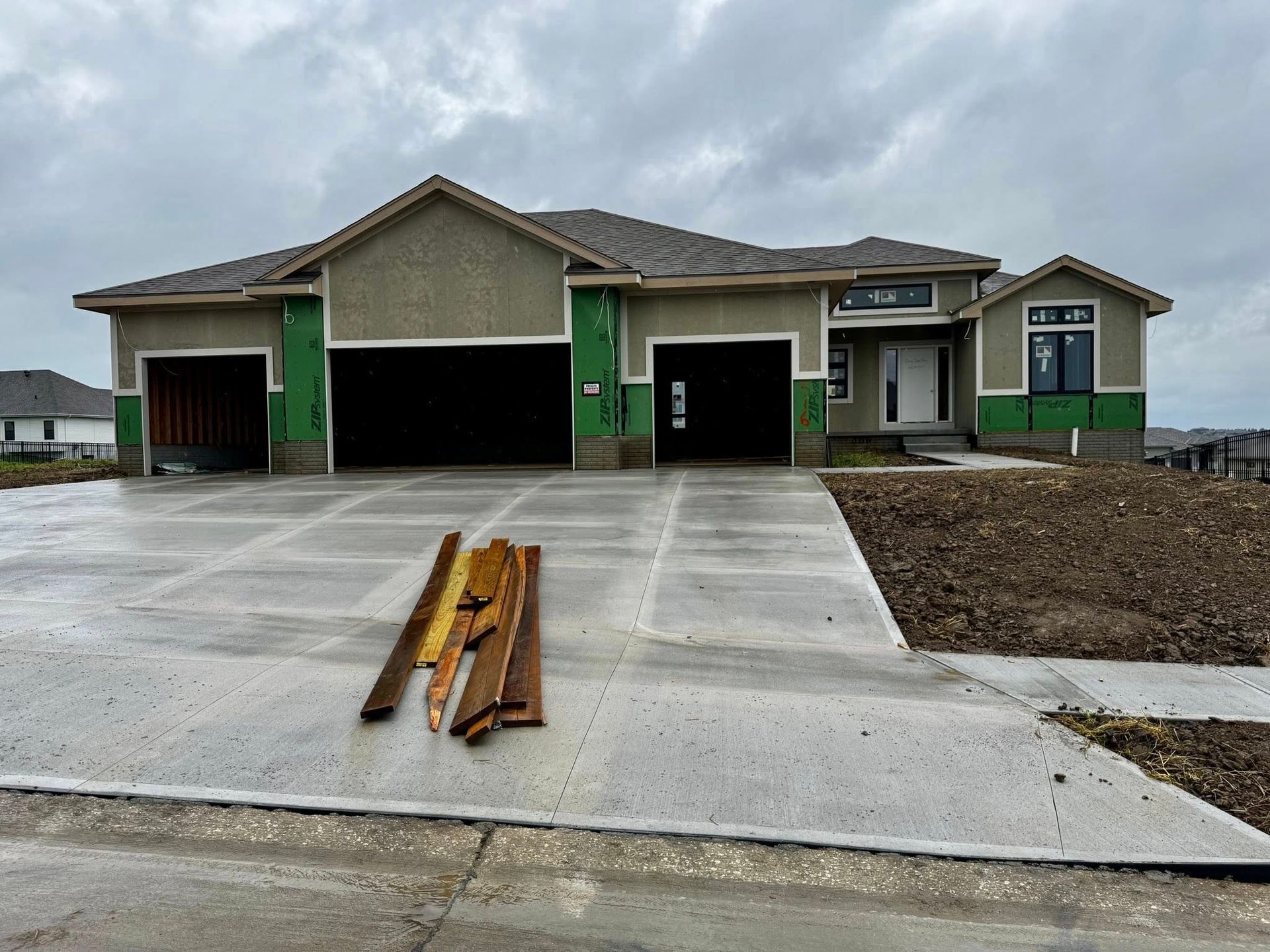 New suburban house under construction with open garage doors and a concrete driveway in front