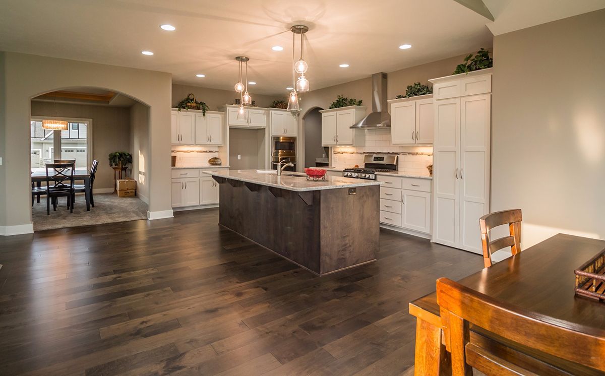 Open kitchen and dining area with dark wood floors, white cabinets, and a wooden table