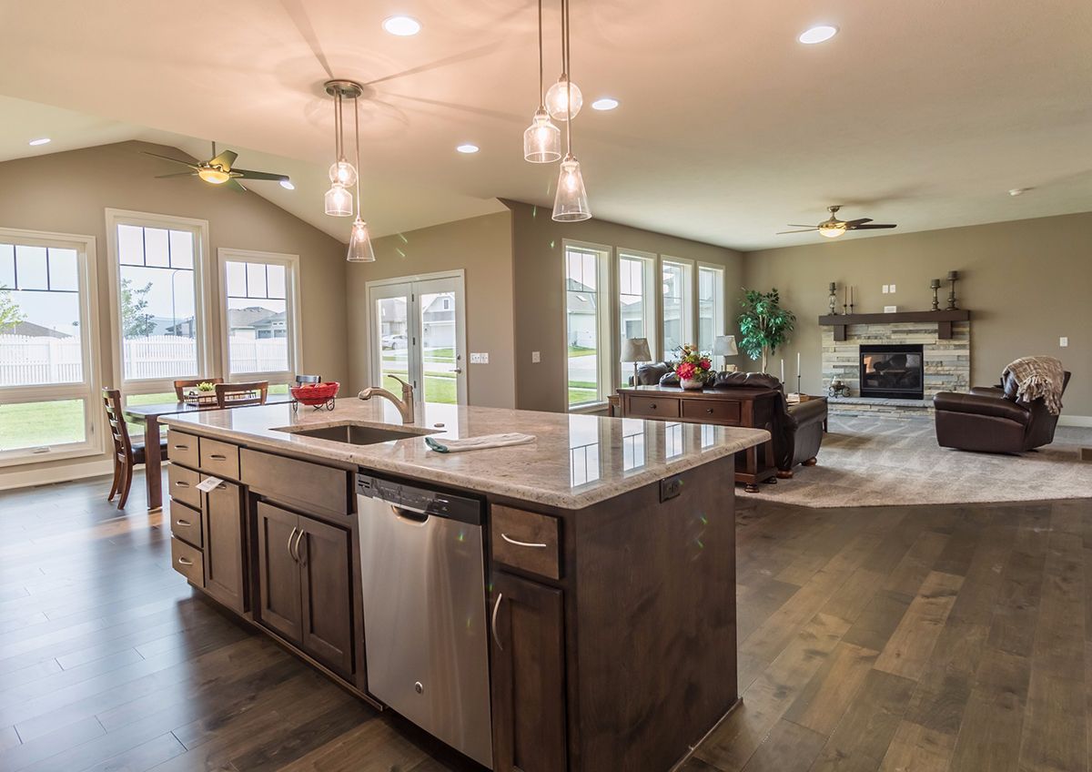 Open-concept kitchen and living room with large island, pendant lights, and fireplace.