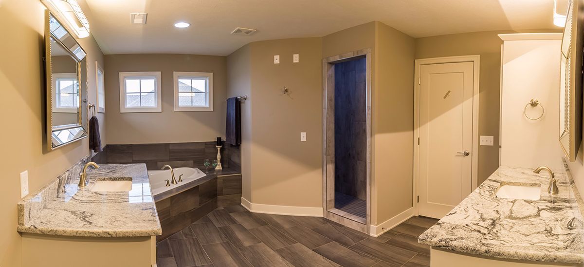 Modern bathroom with double sinks, large mirror, and adjoining bedroom area