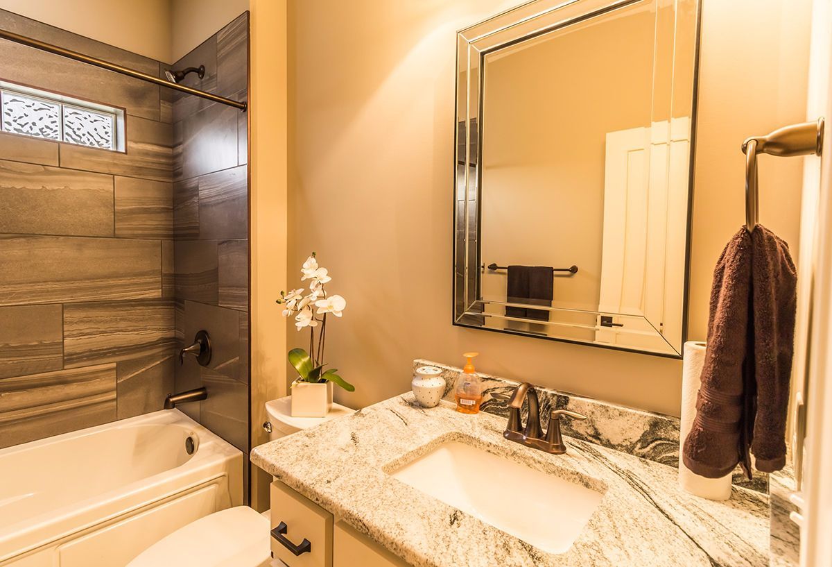 Modern beige bathroom with double vanity, large mirror, bathtub, and dark towel rack