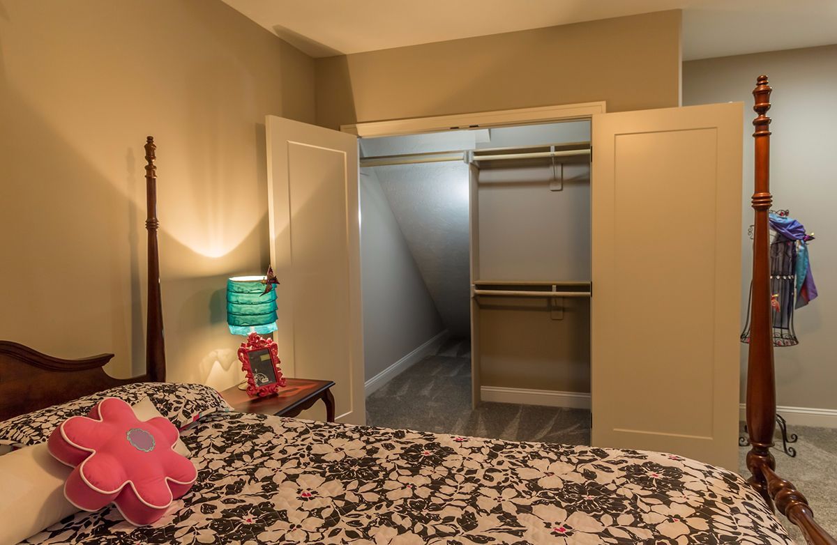 Bedroom with open closet doors and a turquoise lamp beside a bed with a floral comforter.