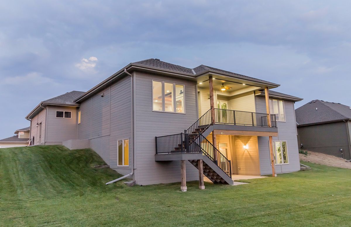 Two-story suburban house at dusk with lit windows, a front staircase, and grassy yard