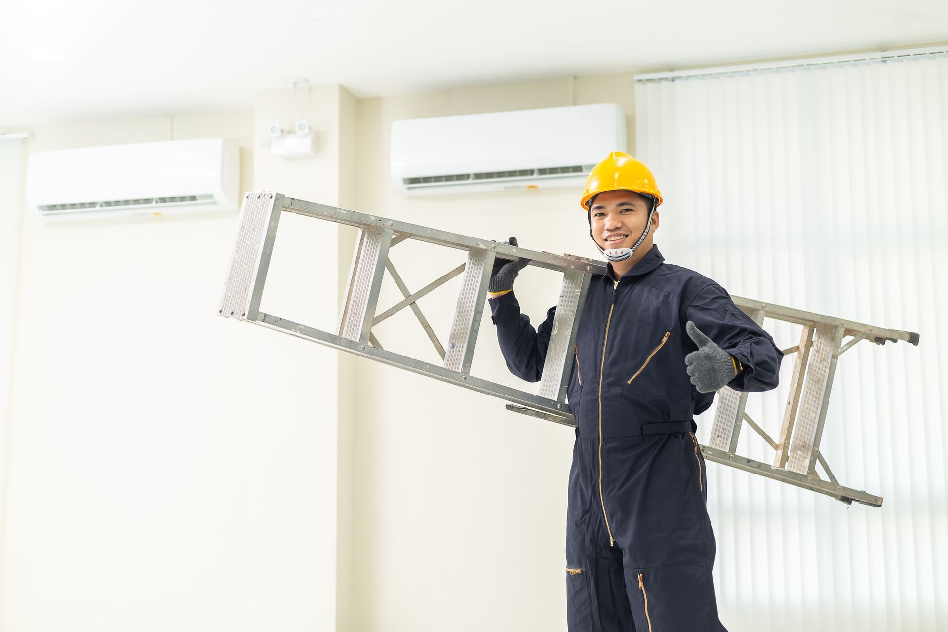 An Air Conditioning Installation Contractor carries a ladder inside an office space. An Air Conditioning Installation Contractor carries a ladder inside an office space.