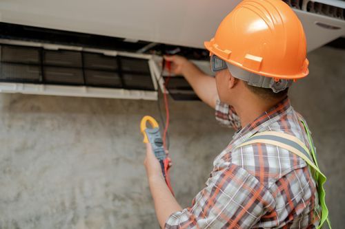 Air conditioning contractor wearing safety gear checks on an AC unit inside a building. — Summit Air Conditioning Service Van in West Palm Beach, FL
