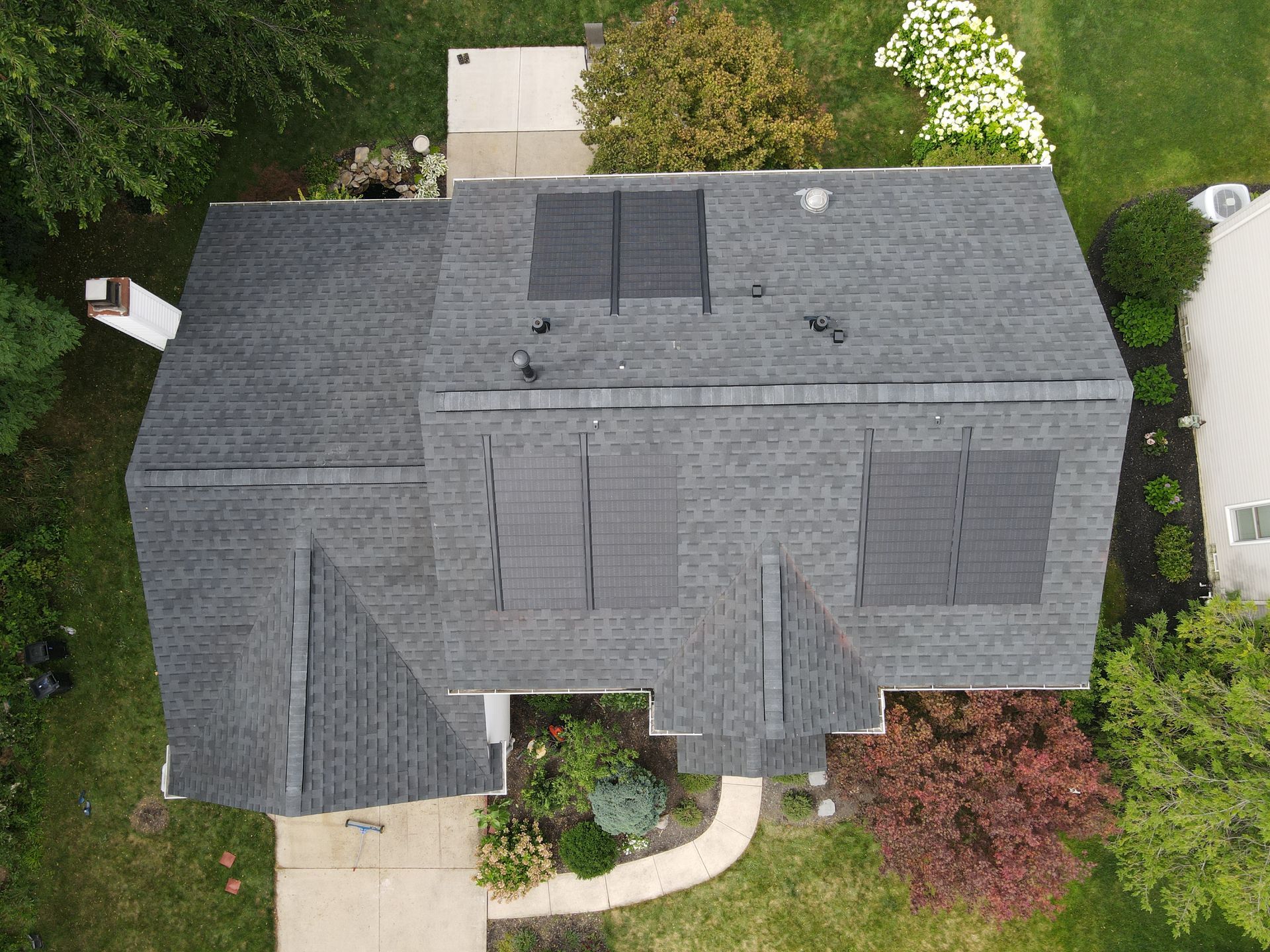 A team of roofing professionals removing old shingles and installing a new roof on a residential home. The workers are ensuring precise alignment and durability, with a neatly organized worksite.