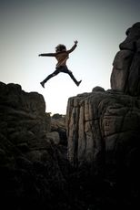 A person is jumping over a rocky cliff