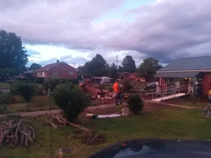 Houses and landscaping, a person in orange shirt working outside. Cloudy sky.