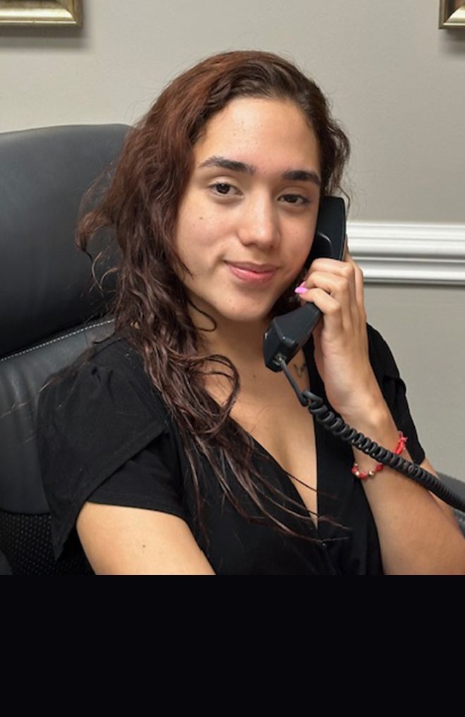 A woman is sitting in a chair talking on a phone.