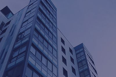 High-rise building with many windows, seen from a low angle, against a blue sky.