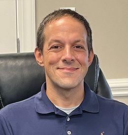 A man is sitting in a chair and smiling for the camera.