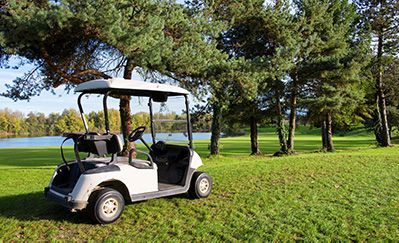 A golf cart is parked in the grass on a golf course.