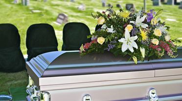 A silver coffin with flowers on top of it in a cemetery.