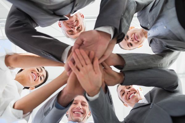 A group of people are putting their hands together in a circle.