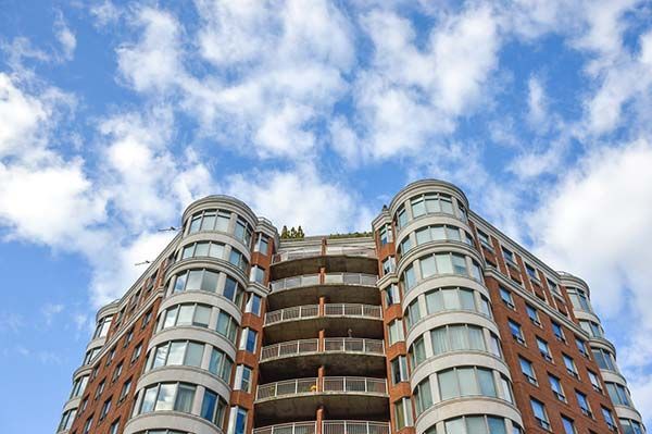 A tall building with a lot of windows against a blue sky with clouds.