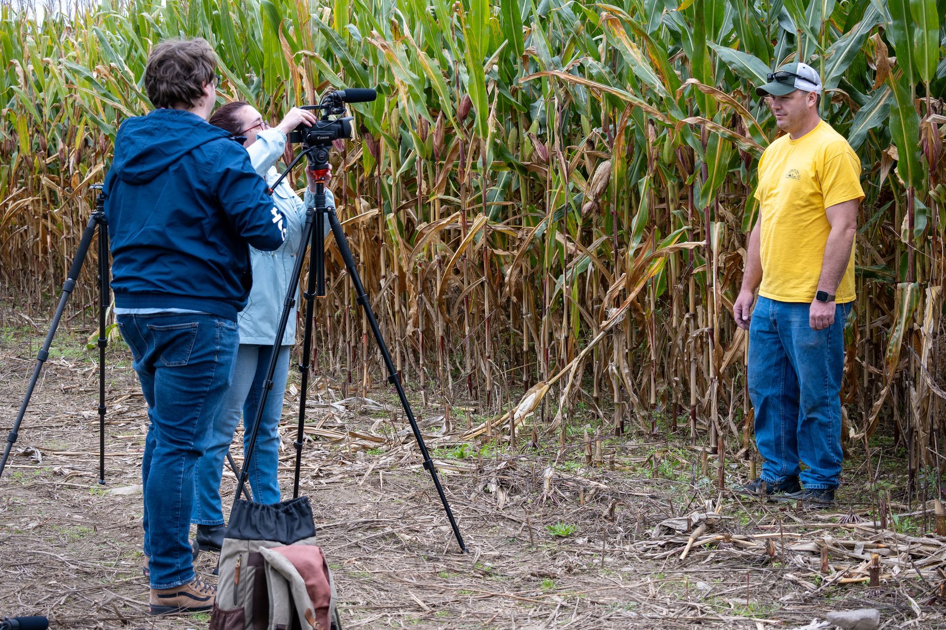 A group of people are standing in front of a corn field.