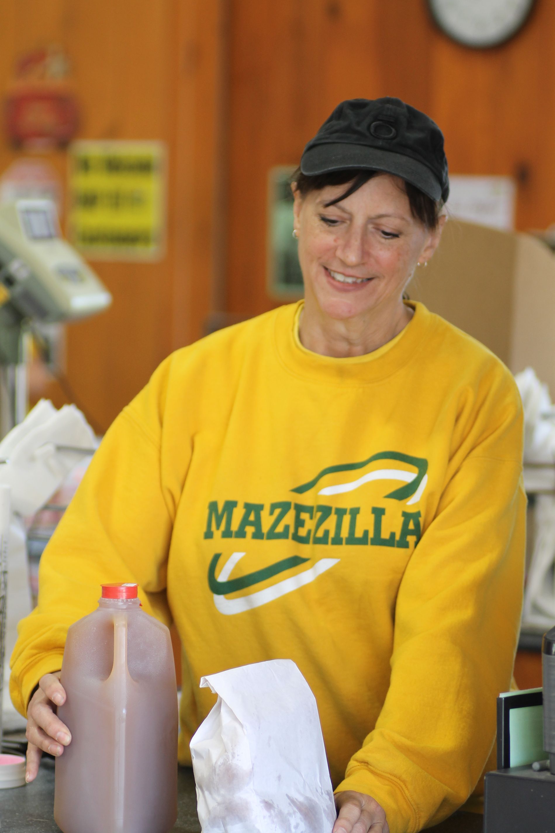 A woman wearing a yellow sweatshirt that says mazezilla
