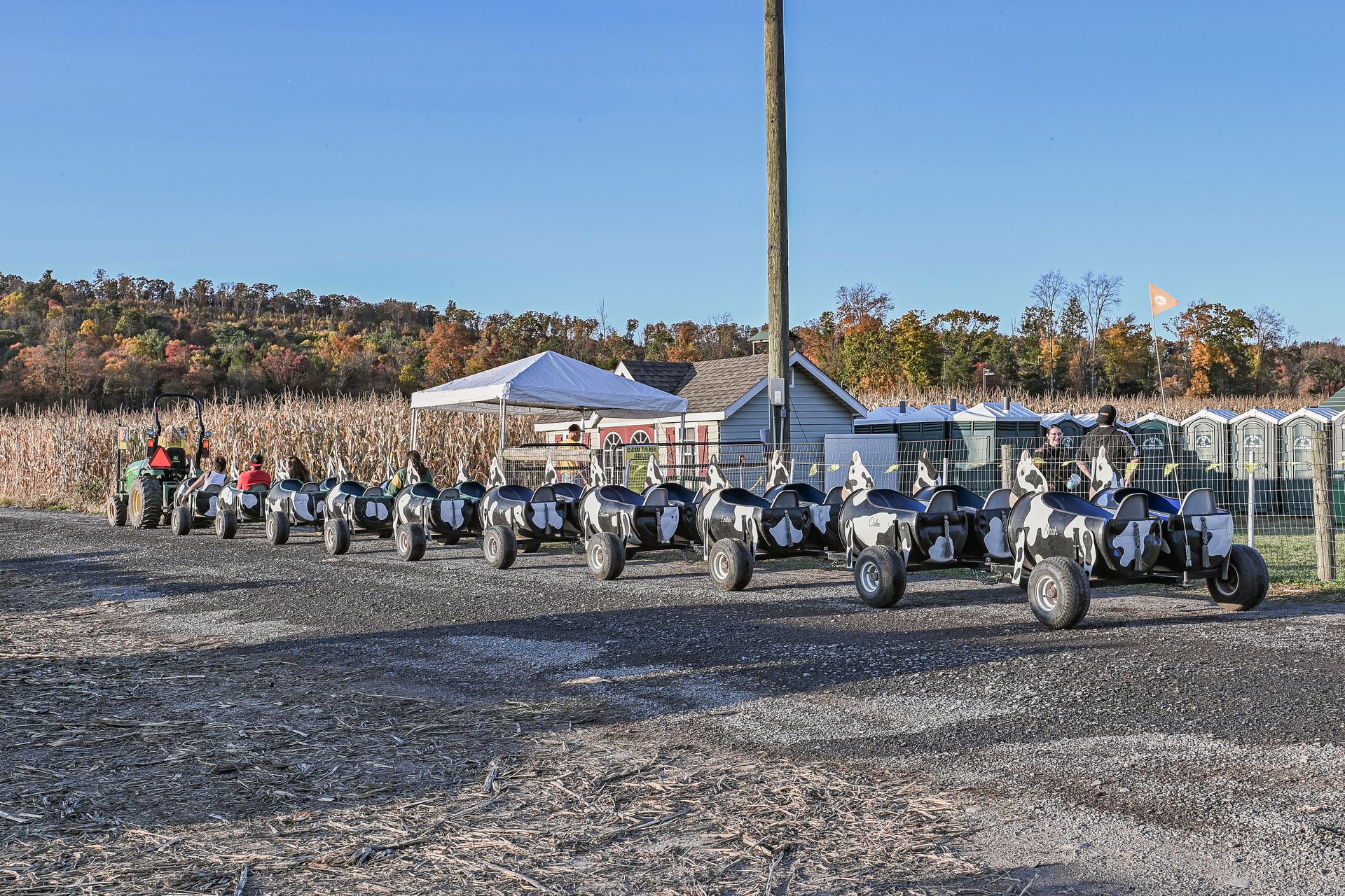 ATVs parked in a gravel lot next to a corn maze and white tent on a sunny day.