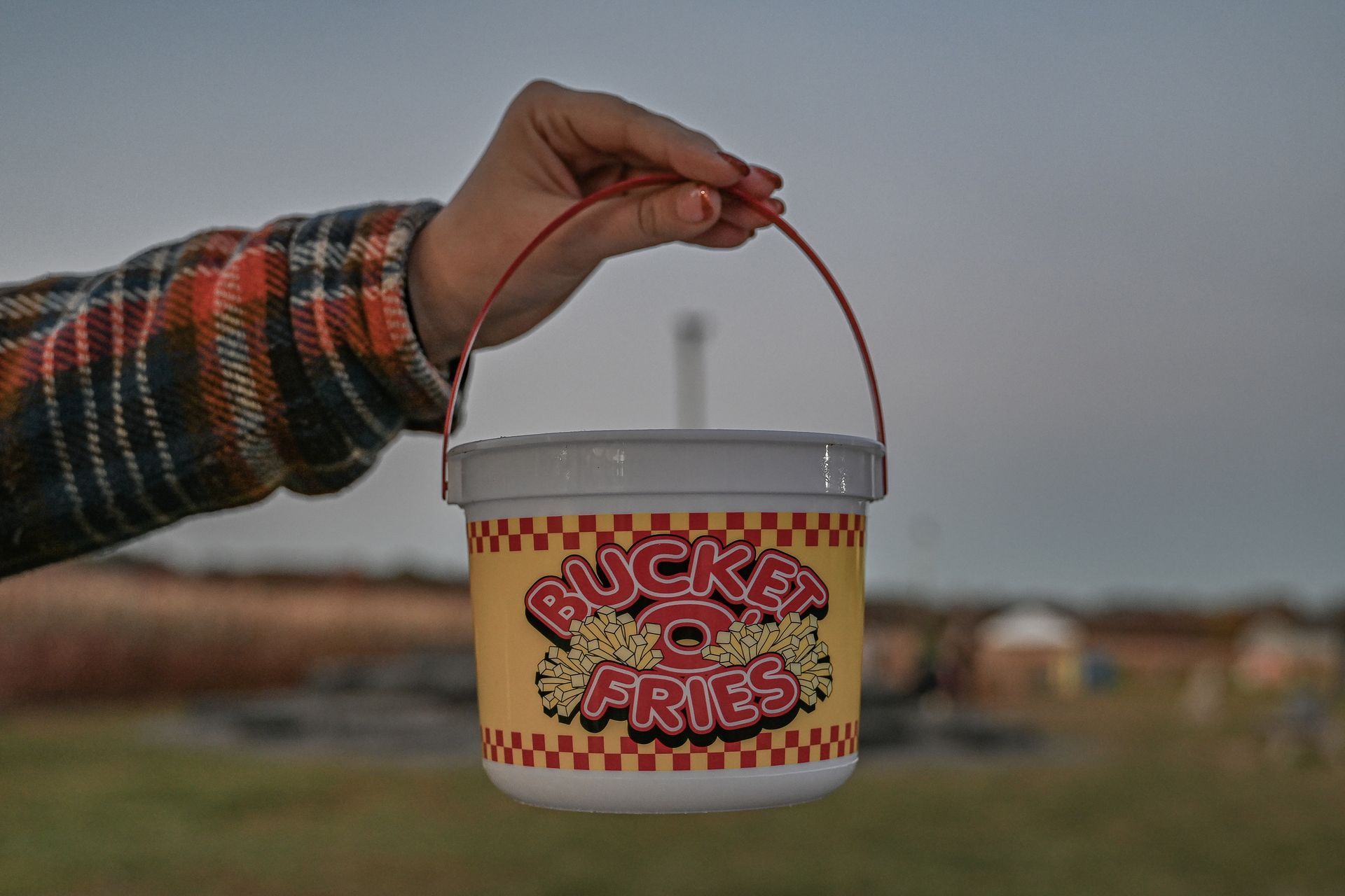 A hand holding a yellow bucket with