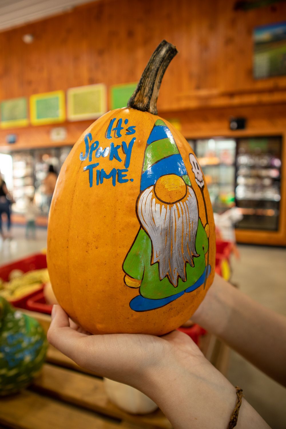 A person is holding a pumpkin with a gnome painted on it.