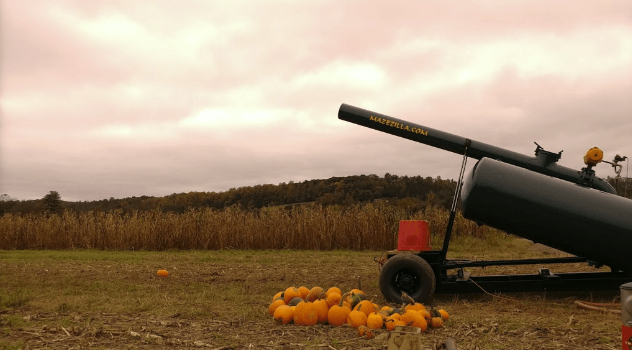 Pumpkin cannon firing pumpkins into the air on a cloudy day in a field.