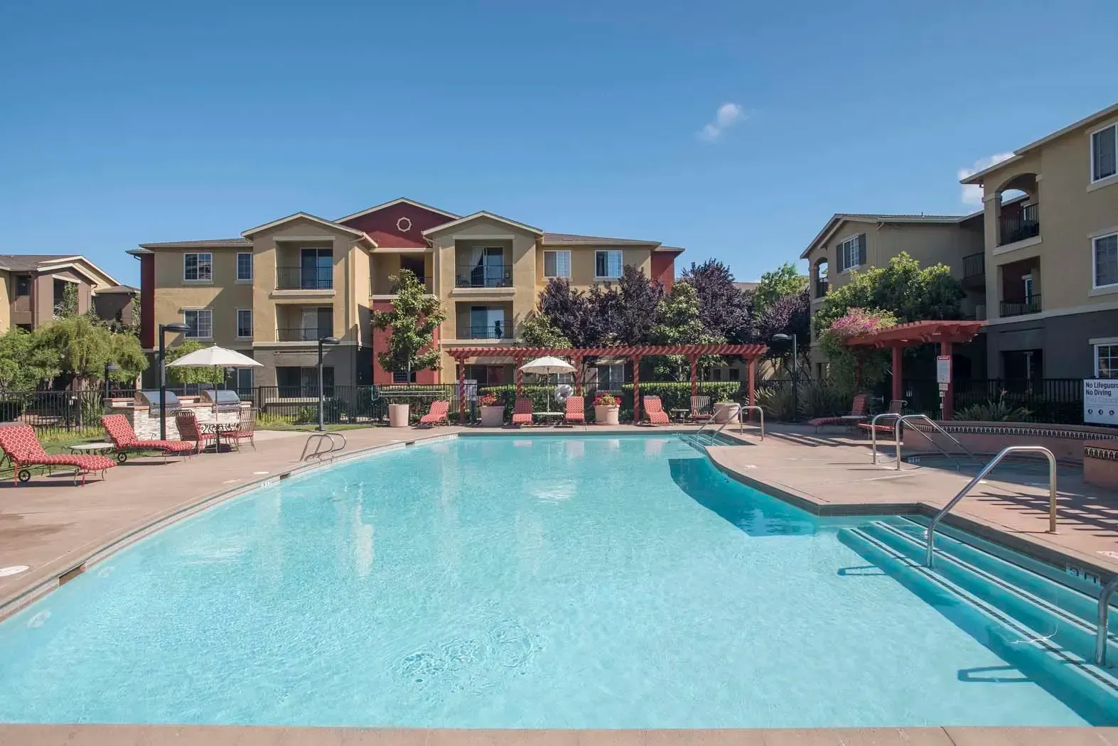 Outdoor swimming pool area with lounge chairs and buildings in the background