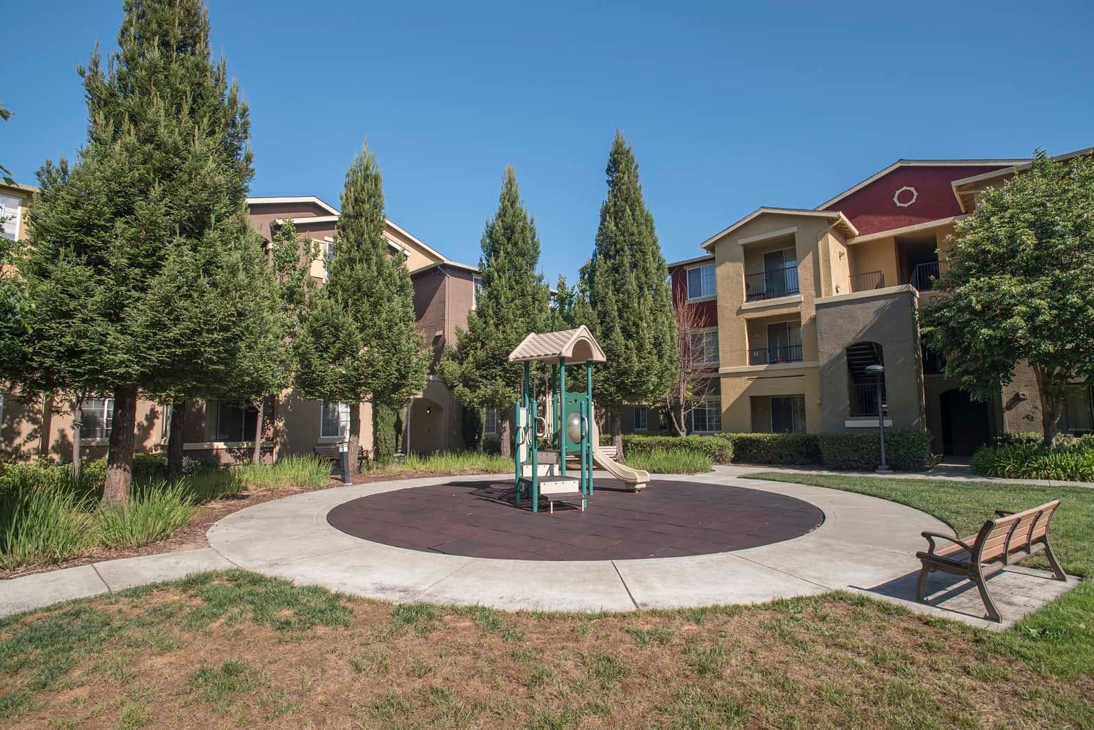 Playground area surrounded by trees and apartment buildings