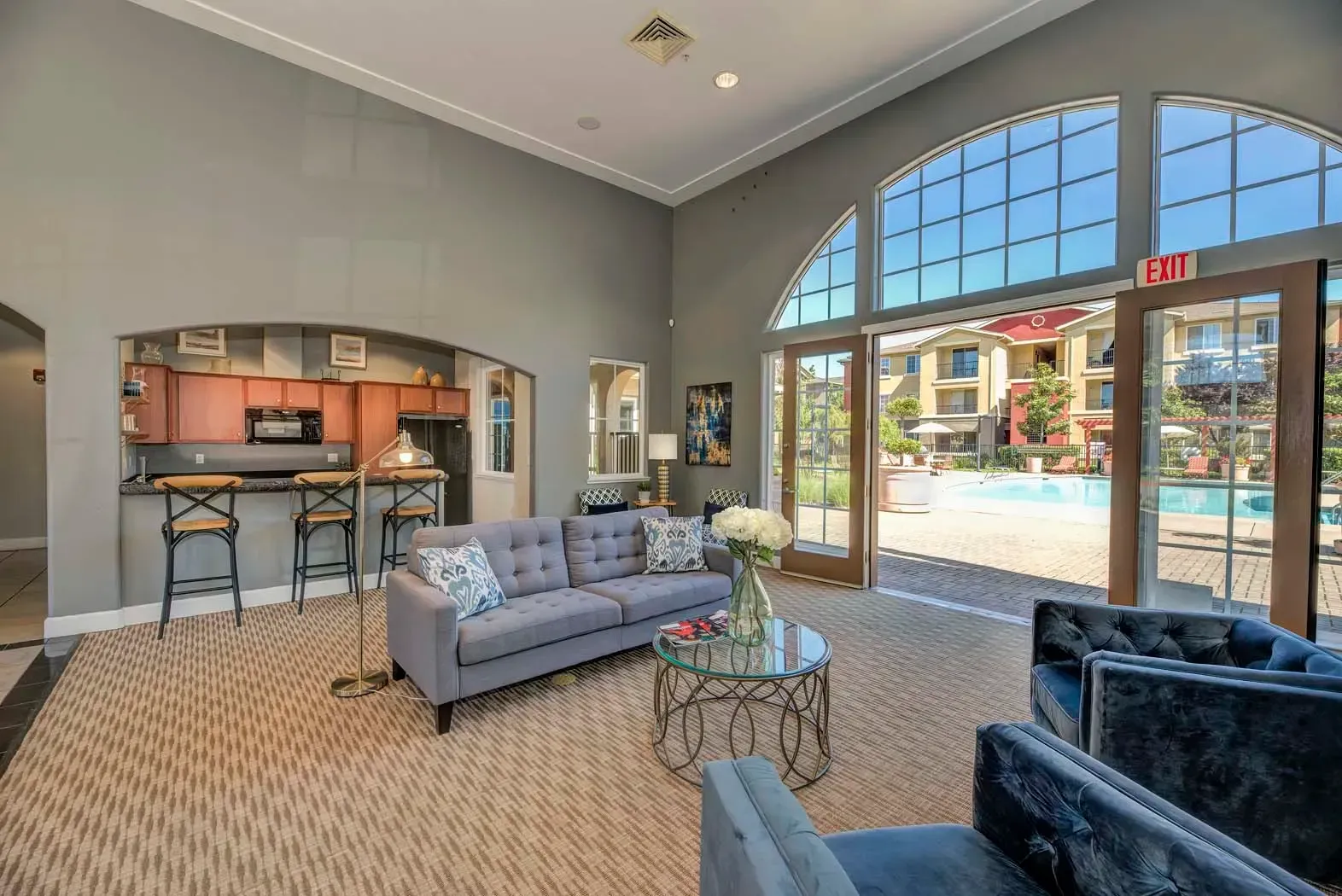 Bright interior lounge area with seating and visible pool area outside.
