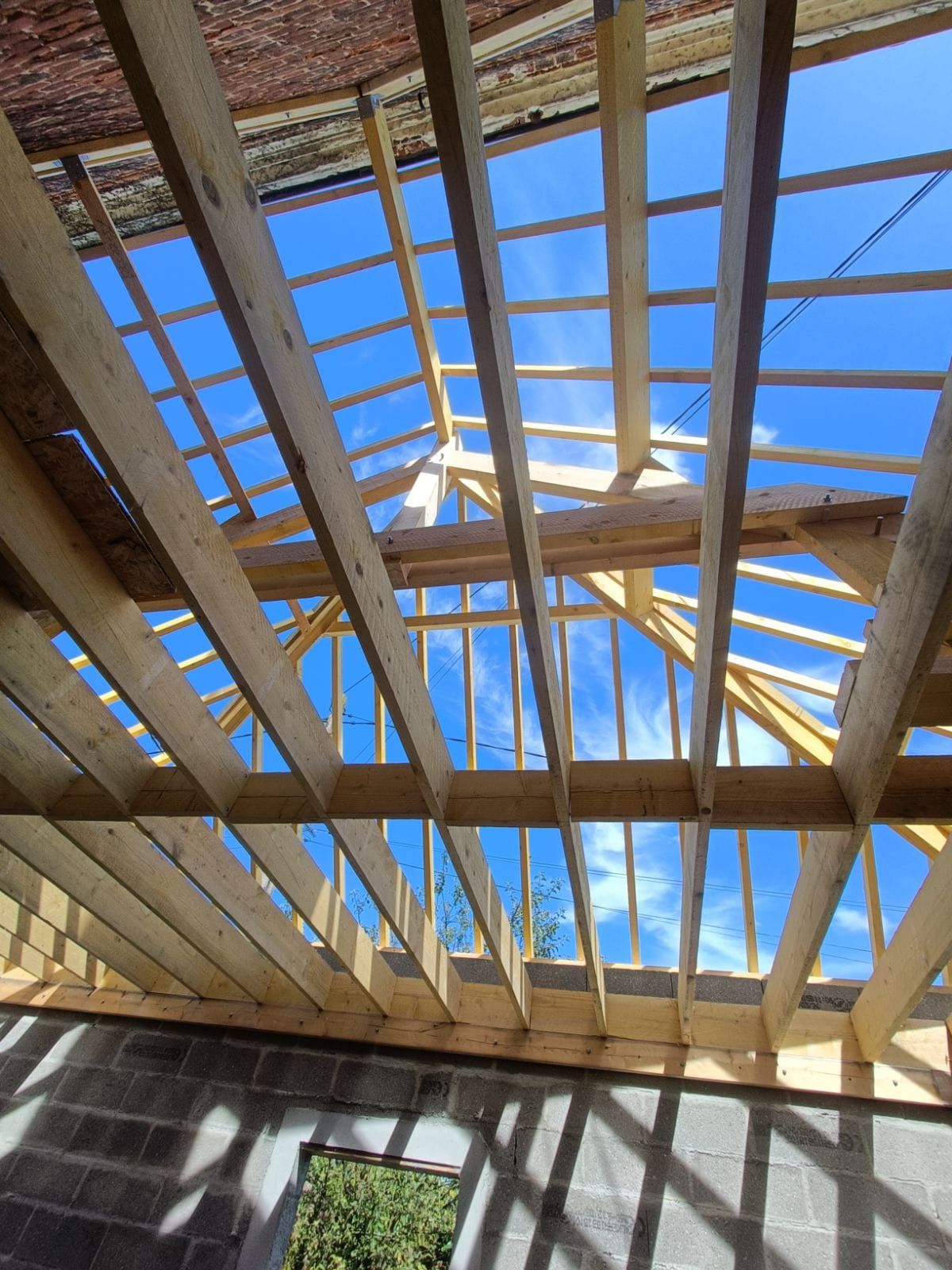 Charpente de toit en bois se détachant sur un ciel d'un bleu éclatant. Chantier.