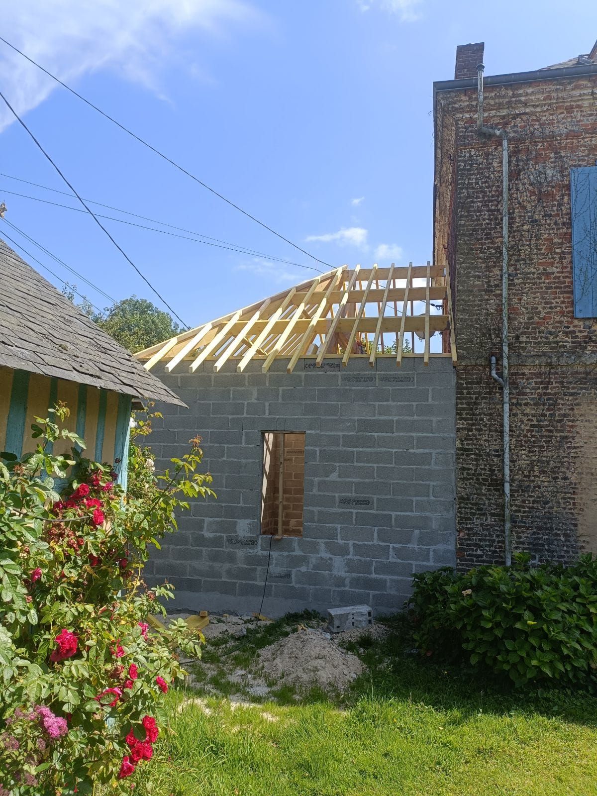 Construction d'un bâtiment en parpaings avec une charpente de toit en bois fixée à une structure en briques