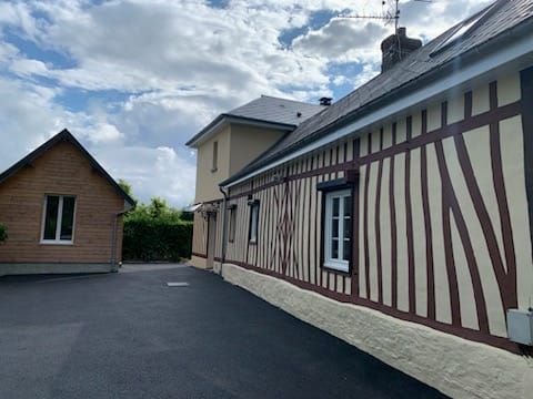 Vue latérale d'un bâtiment à ossature bois et d'une petite structure en bois indépendante ; allée asphaltée.