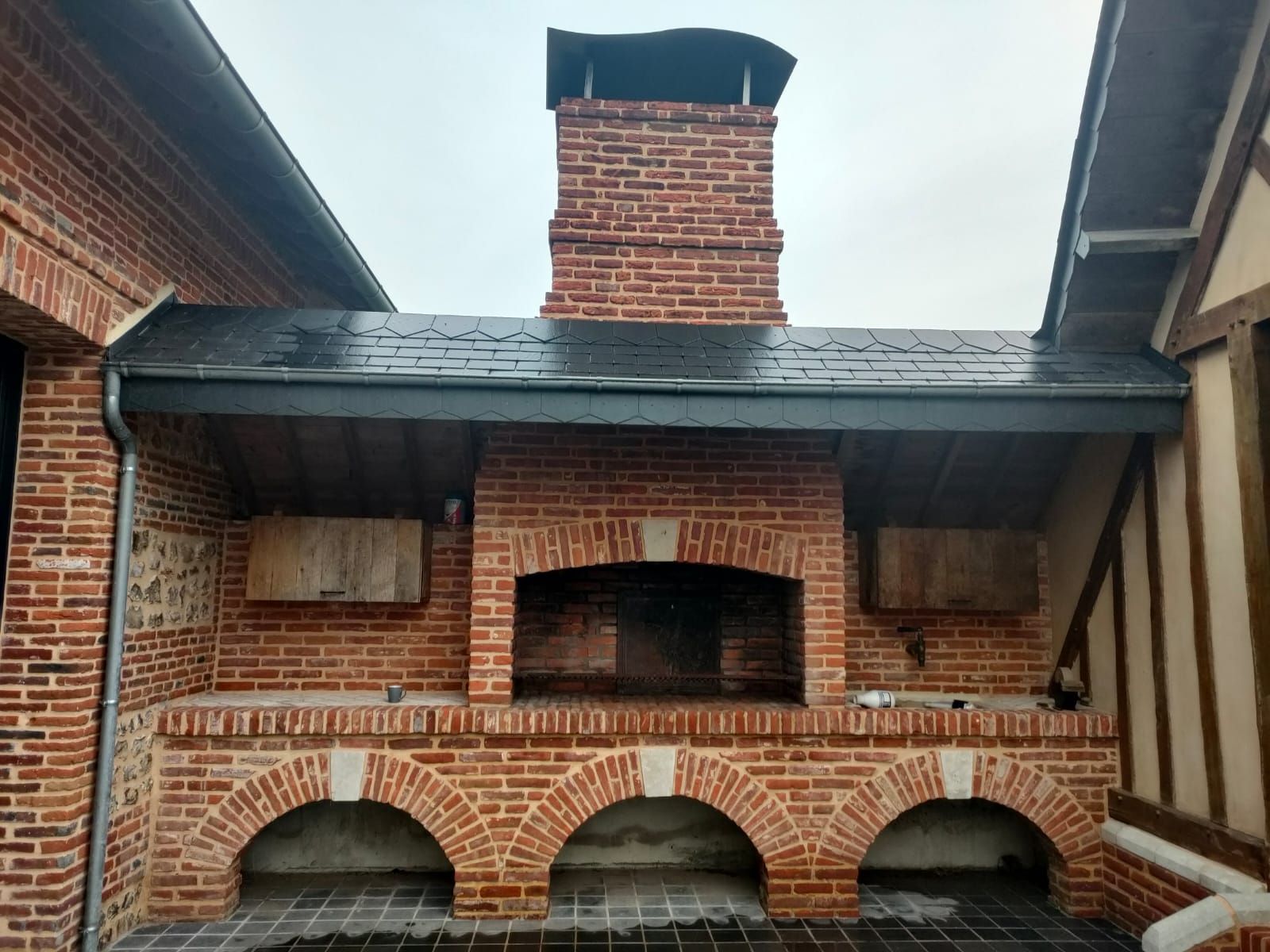 Cheminée extérieure en briques avec trois ouvertures cintrées et un conduit de cheminée.