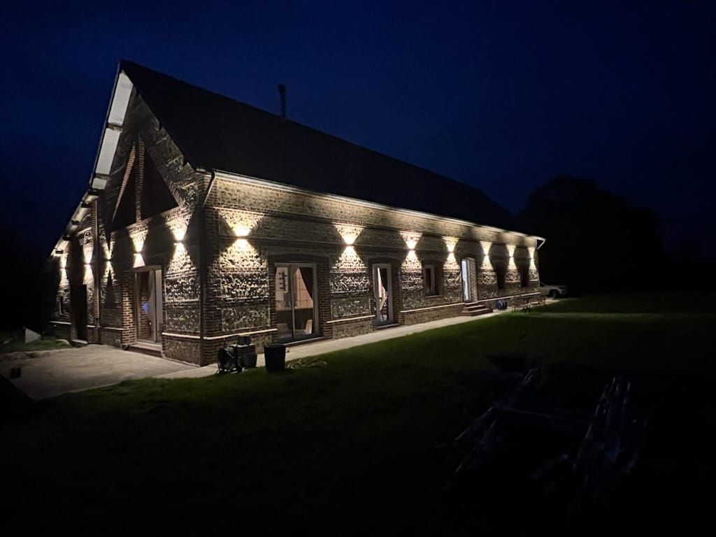 Bâtiment en bois illuminé la nuit par des éclairages extérieurs.