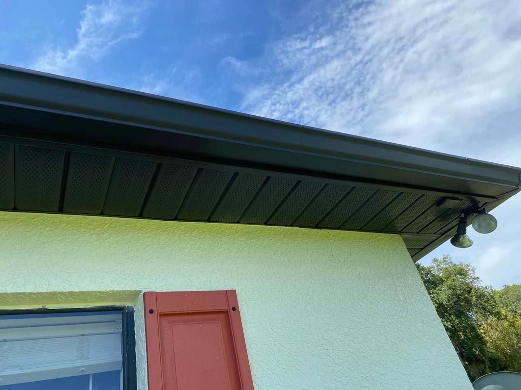 The roof of a house with a window and red shutters.