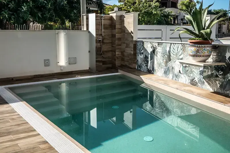 Modern outdoor pool with clean design and tropical-style decor at a Sicilian villa
