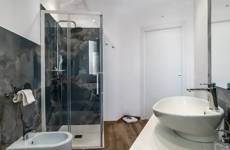 Modern bathroom with glass shower, toilet, sink, and white walls