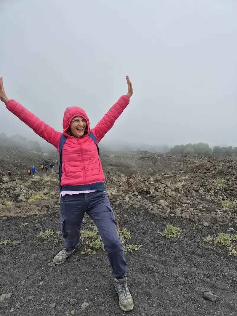 Traveler raising arms on Mount Etna’s volcanic slopes during a guided tour