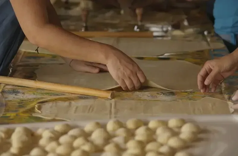 Hands rolling fresh pasta ravioli dough during a traditional Sicilian cooking workshop