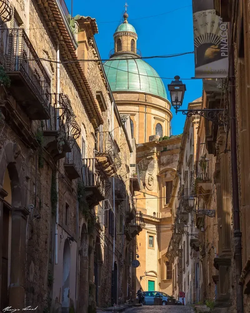 Street view of Piazza Armerina with historic buildings and a church dome