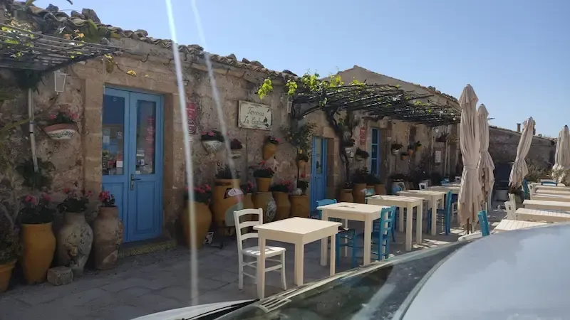 Outdoor café in Piazza Regina Margherita in Marzamemi with rustic stone buildings