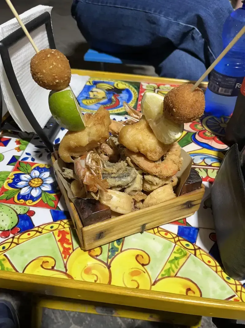 Plate of fresh Sicilian fried seafood with lemon, photographed in a lively outdoor street food