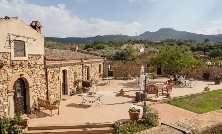 Rustic Sicilian farmhouse courtyard with stone buildings and mountain views