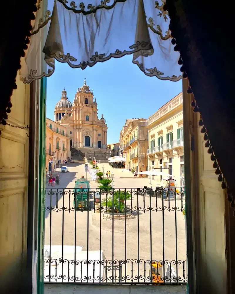 Baroque cathedral dome in Sicily framed by ornate curtains
