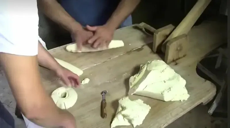 Hands kneading dough on a wooden board during a Sicilian bread‑making class