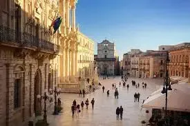 Large square in Ortigia with classical architecture and people walking in the historic center